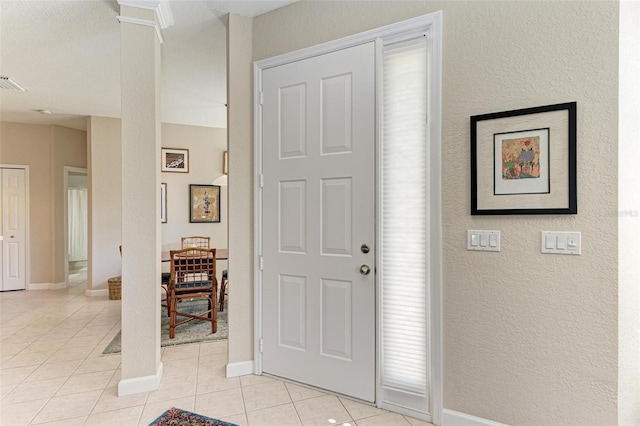 tiled entrance foyer with ornate columns and a textured ceiling