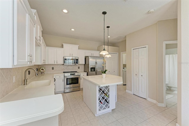 kitchen with hanging light fixtures, sink, white cabinets, and stainless steel appliances