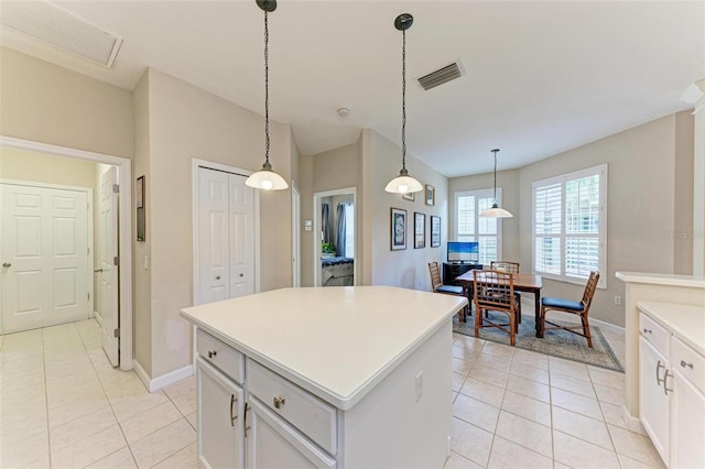 kitchen featuring hanging light fixtures, a center island, white cabinets, and light tile patterned flooring