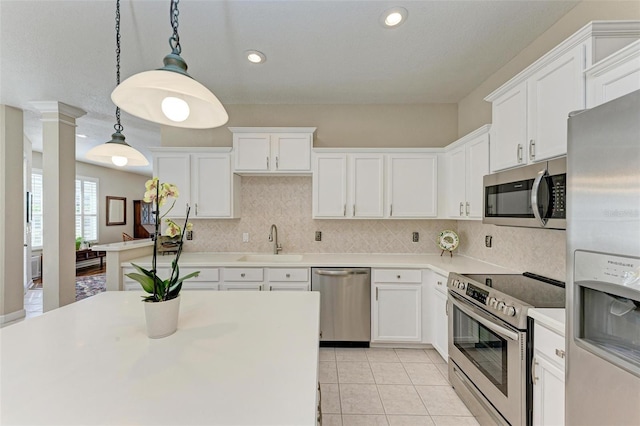 kitchen featuring appliances with stainless steel finishes, sink, white cabinets, hanging light fixtures, and light tile patterned flooring