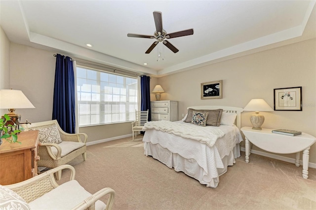 carpeted bedroom featuring ceiling fan and a tray ceiling