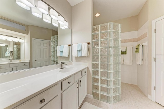 bathroom with tile patterned flooring, vanity, and tiled shower