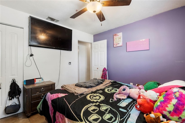 tiled bedroom with ceiling fan and a closet