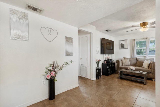 tiled living room with ceiling fan and a textured ceiling