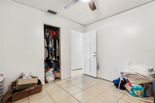 tiled bedroom featuring a textured ceiling, a closet, ceiling fan, and ornamental molding