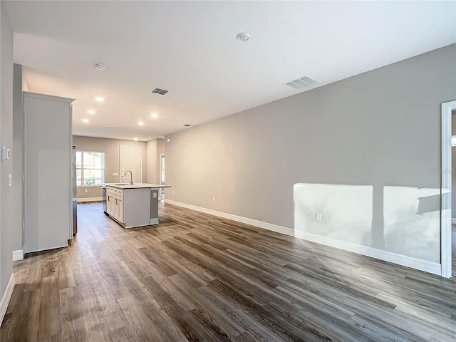 kitchen featuring sink, dark hardwood / wood-style flooring, and an island with sink