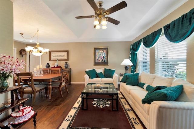 living room with a tray ceiling, ceiling fan with notable chandelier, and dark hardwood / wood-style floors