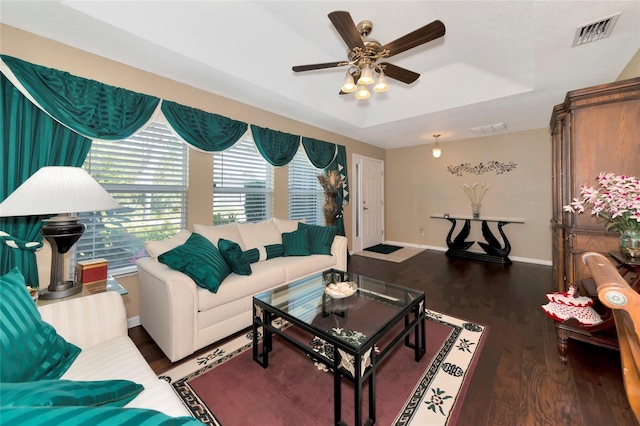 living room featuring dark hardwood / wood-style floors, ceiling fan, and a tray ceiling