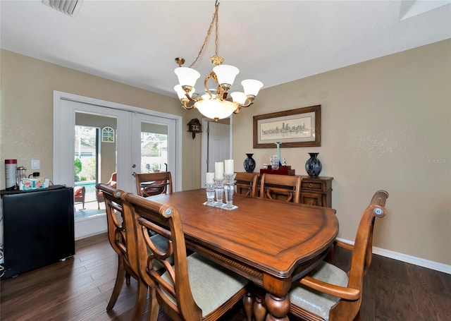 dining area with dark hardwood / wood-style floors, an inviting chandelier, and french doors