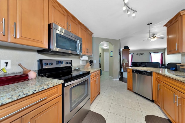 kitchen featuring light stone counters, light tile patterned floors, stainless steel appliances, and ceiling fan