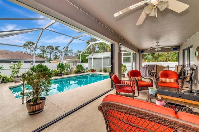 view of swimming pool with ceiling fan, an outdoor hangout area, glass enclosure, and a patio area