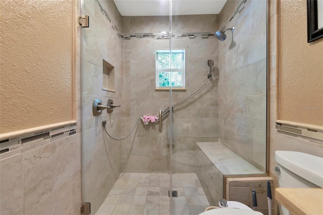 bathroom with a shower with door, tile walls, and toilet