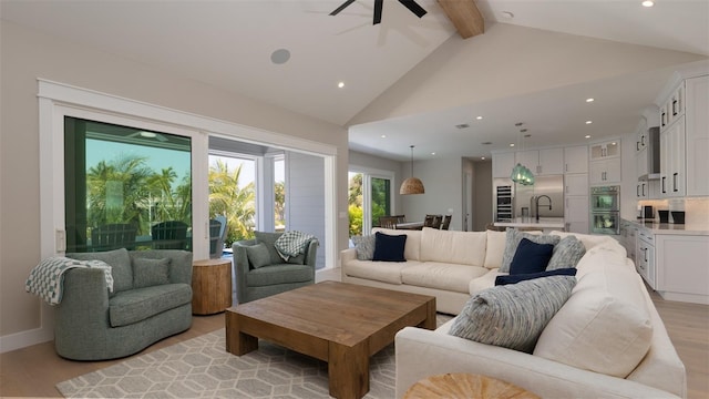 living room with ceiling fan, beamed ceiling, high vaulted ceiling, and light wood-type flooring