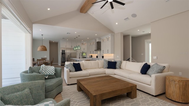 living room with beam ceiling, ceiling fan, sink, and high vaulted ceiling