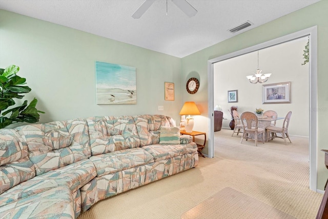 carpeted living room featuring a textured ceiling and ceiling fan with notable chandelier