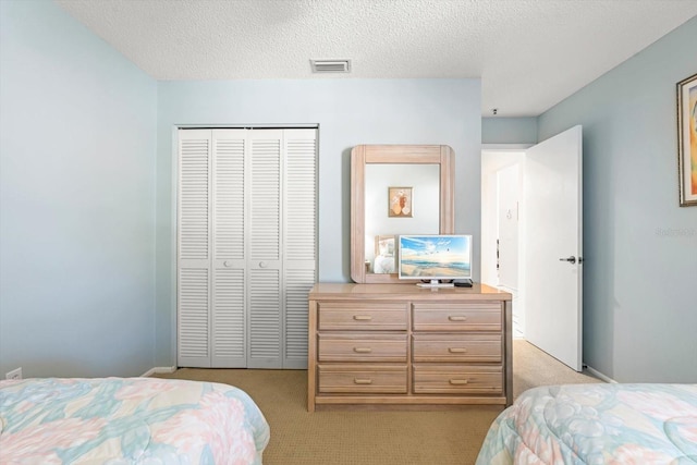 bedroom with a textured ceiling, light colored carpet, and a closet