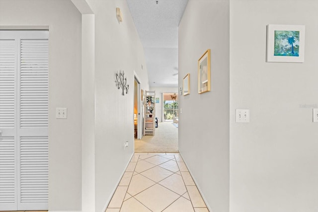 corridor with light tile patterned floors and a textured ceiling