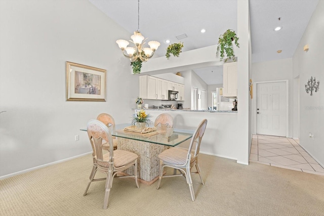 dining area featuring a chandelier, light colored carpet, and high vaulted ceiling