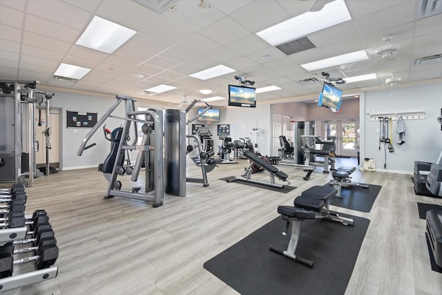 exercise room featuring a paneled ceiling and light wood-type flooring