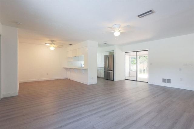 unfurnished living room with light wood-type flooring and ceiling fan