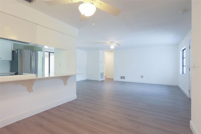 unfurnished living room featuring dark hardwood / wood-style floors, ceiling fan, and a wealth of natural light