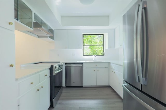 kitchen with sink, appliances with stainless steel finishes, decorative backsplash, white cabinets, and light wood-type flooring