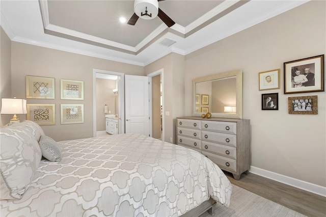 bedroom with ensuite bathroom, ornamental molding, wood-type flooring, and a raised ceiling