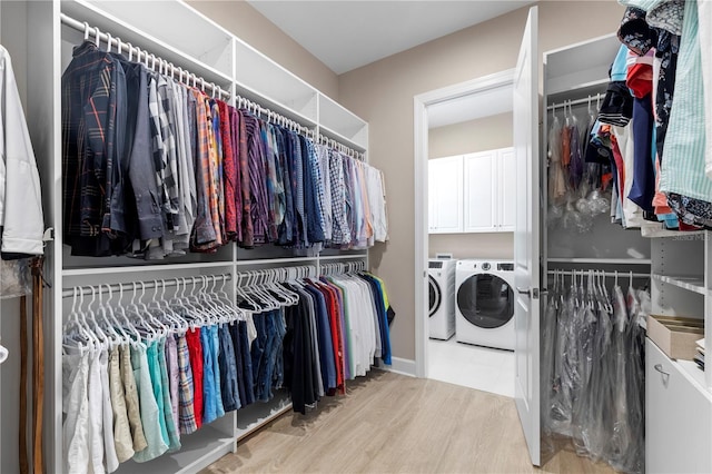 walk in closet with light hardwood / wood-style floors and independent washer and dryer