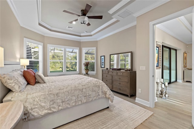 bedroom with ceiling fan, ornamental molding, a raised ceiling, and light hardwood / wood-style flooring