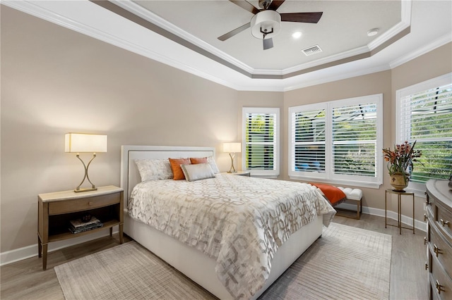 bedroom featuring crown molding, ceiling fan, a tray ceiling, and light wood-type flooring