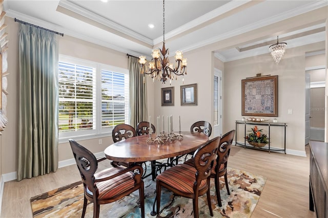 dining area with light hardwood / wood-style floors, an inviting chandelier, and a tray ceiling