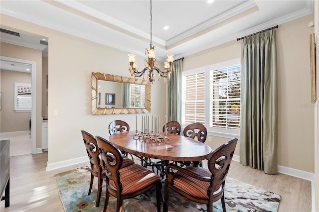 dining room with a chandelier, ornamental molding, a raised ceiling, and light hardwood / wood-style flooring