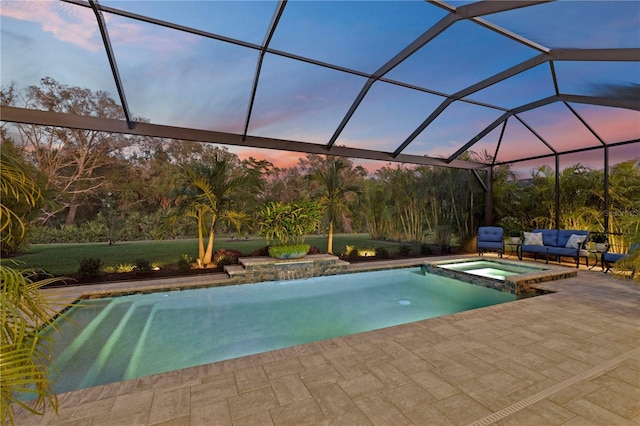 pool at dusk featuring an in ground hot tub, a lanai, an outdoor hangout area, and a patio