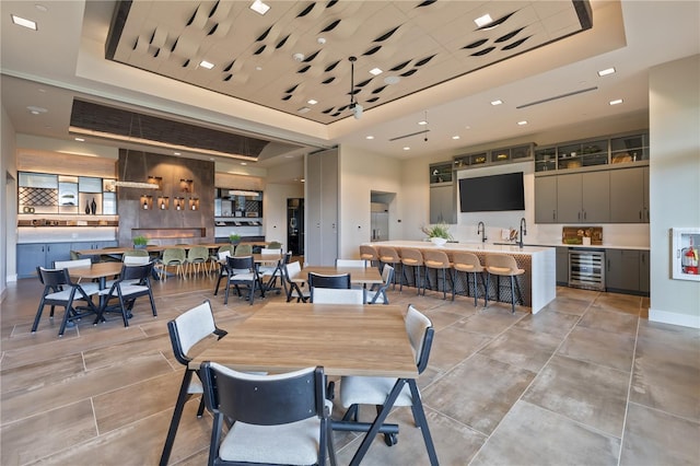 dining space with beverage cooler, a raised ceiling, and indoor wet bar