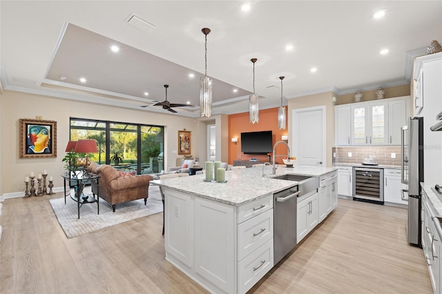 kitchen with sink, a center island with sink, appliances with stainless steel finishes, beverage cooler, and white cabinets