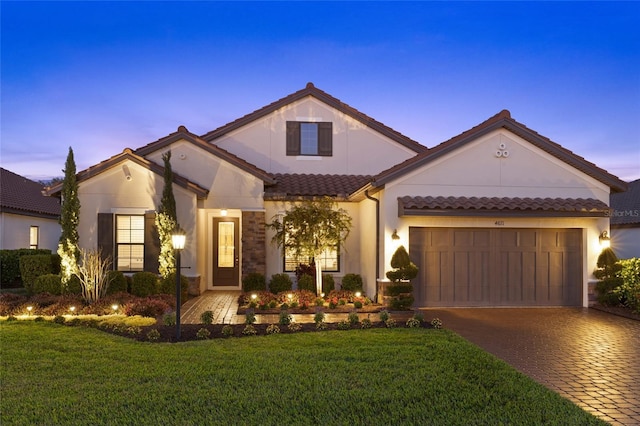 mediterranean / spanish house with a garage and a lawn