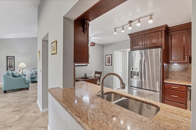 kitchen with sink, stainless steel fridge with ice dispenser, light stone counters, lofted ceiling, and decorative backsplash