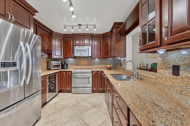 kitchen featuring backsplash, sink, light stone countertops, stainless steel appliances, and beverage cooler