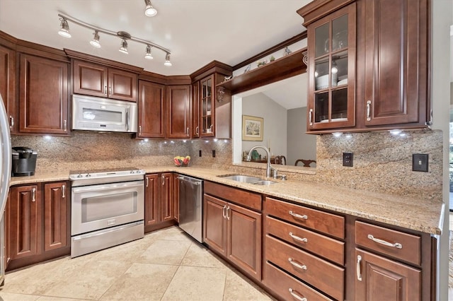 kitchen featuring decorative backsplash, stainless steel appliances, light stone counters, and sink