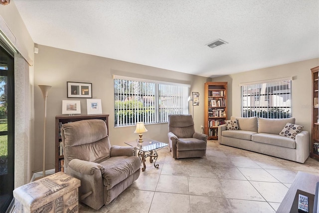 living room featuring a wealth of natural light, light tile patterned flooring, and a textured ceiling