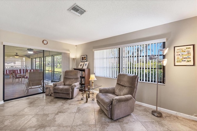 living area with ceiling fan and a textured ceiling