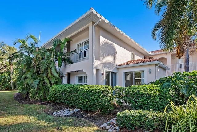 view of property exterior featuring stucco siding, a tile roof, and a balcony