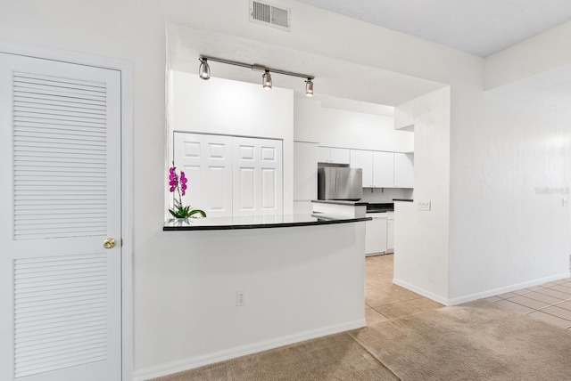 kitchen featuring white cabinets, stainless steel fridge, and light tile patterned floors