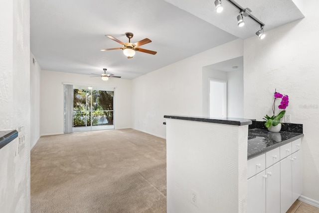 unfurnished living room with light carpet, ceiling fan, and rail lighting