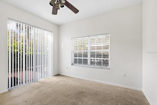 carpeted empty room featuring a wealth of natural light and ceiling fan