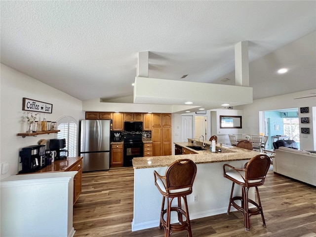 kitchen with black appliances, a breakfast bar, lofted ceiling, and dark wood-type flooring