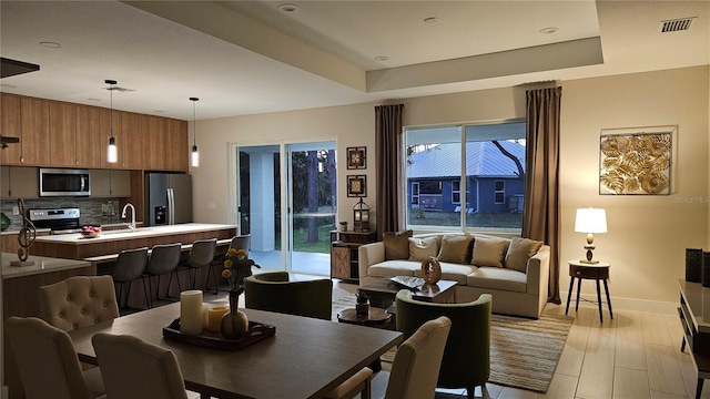 dining area featuring a raised ceiling and sink