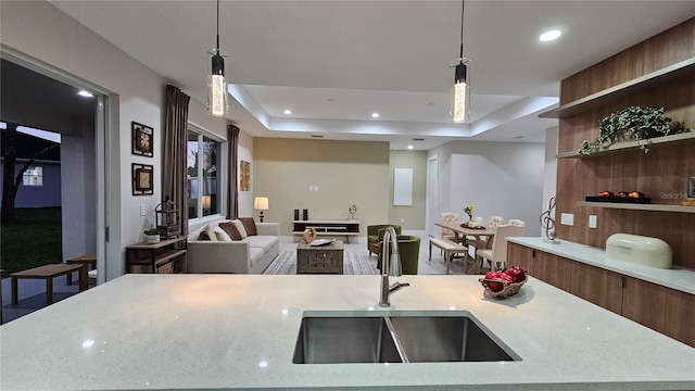 kitchen featuring a raised ceiling, light stone counters, and decorative light fixtures