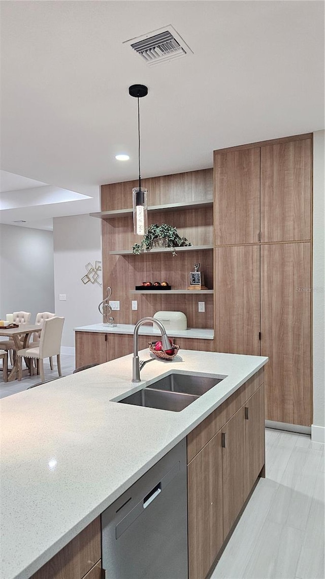 kitchen with dishwasher, decorative light fixtures, light stone countertops, and sink