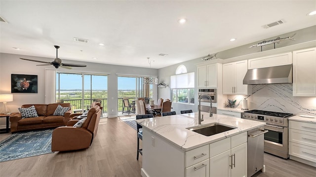 kitchen featuring appliances with stainless steel finishes, white cabinetry, extractor fan, and sink